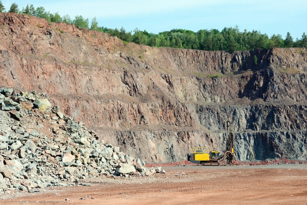 Driller in an open pit mine. porphyry rock material.